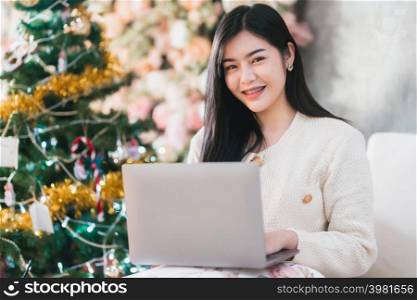 Portrait freelance business smile young asian woman holding cup coffee online working with laptop computer at home in the living room indoors Decoration During Christmas x-mas and New Year holidays.
