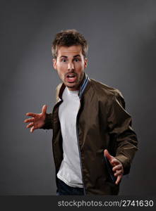 Portrait from the waist up of a caucasian man who is surprised and scared. Studio shot on a gray background.