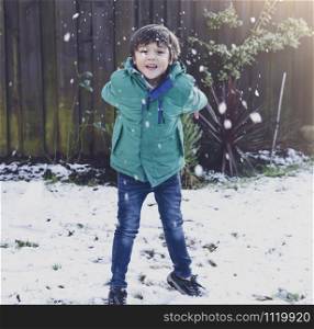Portrait funny joyful happy child boy throwing up the snow. Selective focus of kid playing with snow outdoor in early winter