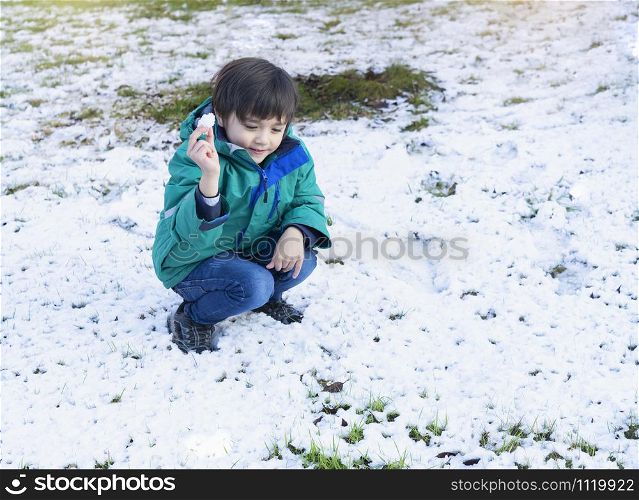 Portrait funny joyful happy child boy throwing up the snow. Selective focus of kid playing with snow outdoor in early winter