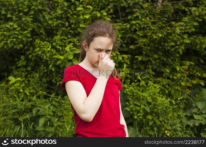portrait girl holding nose green nature looking camera