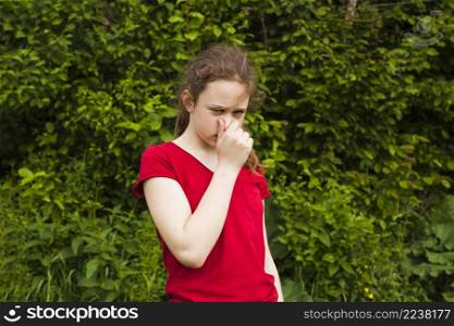 portrait girl holding nose green nature looking camera