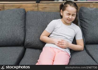 portrait girl sitting gray sofa having sever pain stomach