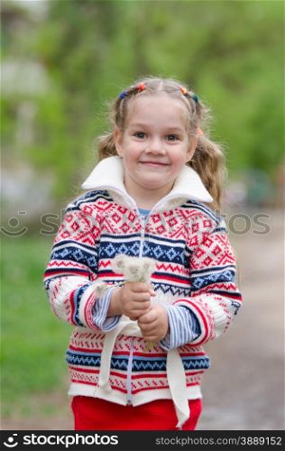 Portrait girl with a bouquet white dandelions in the hands of. Half-length portrait four-year girl in a jacket with a bouquet of dandelions in the hands of