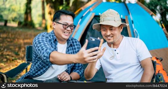 Portrait happy Asian man friends Making a video call with smartphone in c&ing. Cooking set front ground. Outdoor cooking, traveling, c&ing, lifestyle concept.
