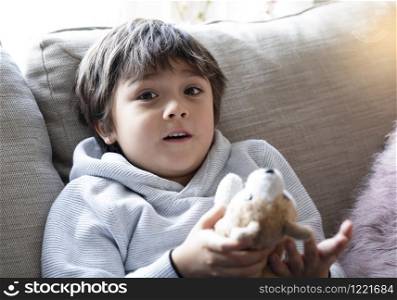 Portrait Happy boy lying on sofa playing with dog toy, A Child boy with surprised face playing with his toy relaxing at home on weekend. Positive children concept