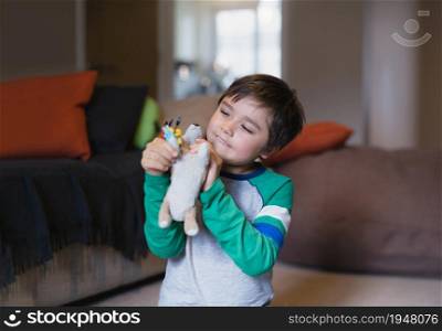 Portrait happy Child boy playing with dog toy in living room, Positive young kid having fun playing with his toys relaxing at home after back from school