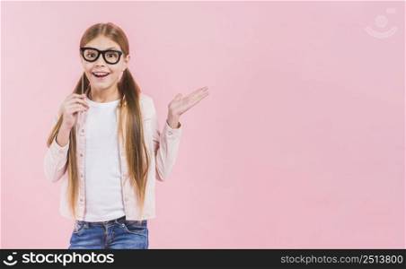 portrait happy girl holding eyeglasses prop shrugging against pink background