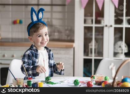 portrait happy little boy painting easter eggs