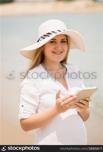 Portrait happy woman posing with digital tablet at windy beach