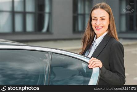 portrait happy young businesswoman standing near open car door