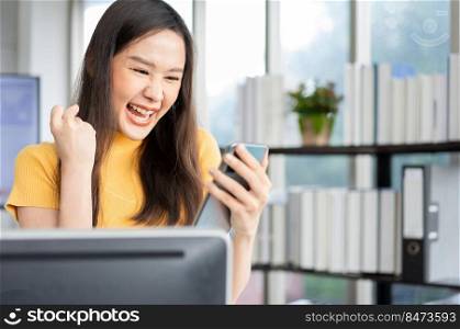 Portrait happy young programmer Asian woman work at start up technology office and using smartphone and testing mobile application and excited in success. Concept of smart entrepreneur woman working.