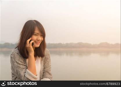 Portrait happy young woman smiling and walking in the street using talking on a smartphone and looking at camera