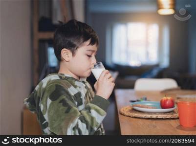 Portrait healthy school boy drinking glass of milk for breakfast, Happy child sitting in dining room drinking warm milk before go to school. Healhty food liftstyle concept