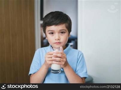 Portrait healthy school boy drinking glass of milk for breakfast, Happy child standing in kitchen drinking warm milk before go to school. Healhty food liftstyle concept