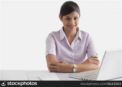 Portrait if young businesswoman sitting at desk with laptop