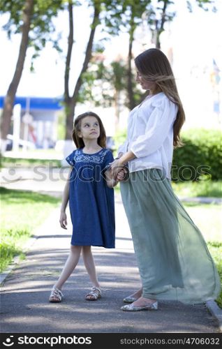 Portrait in full growth, mother and eight year old daughter in a summer park