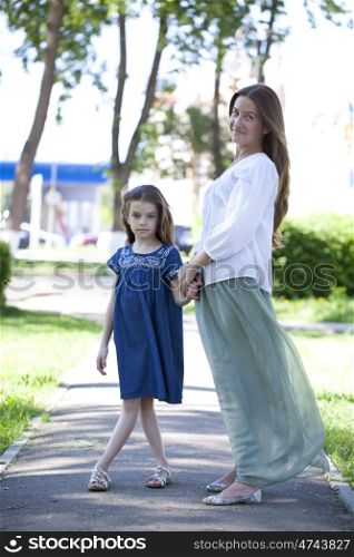 Portrait in full growth, mother and eight year old daughter in a summer park