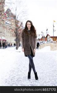 Portrait in full growth of a beautiful stylish young woman on the background Red Square, Moscow Kremlin, Russia