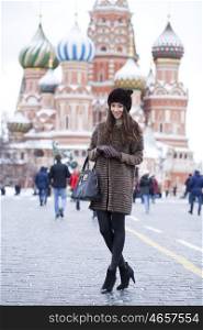 Portrait in full growth of a beautiful stylish young woman on the background of St. Basil's Cathedral, Moscow Kremlin, Russia