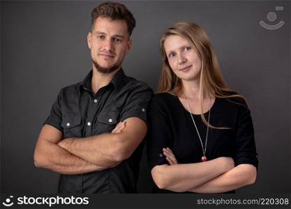 Portrait in the studio of two young and happy business people and partners standing with crossed hands at their chest