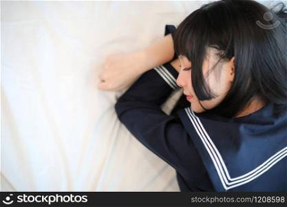 Portrait japanese school girl sleeping in white tone bed room