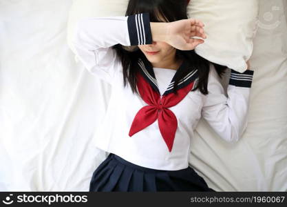 Portrait japanese school girl sleeping with pillow in white tone bed room