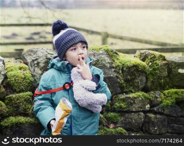 Portrait kid eating crisps while walking at farmalnd, Cute little boy eating snack or picnic food in the park, Outdoor activity with school camp concept