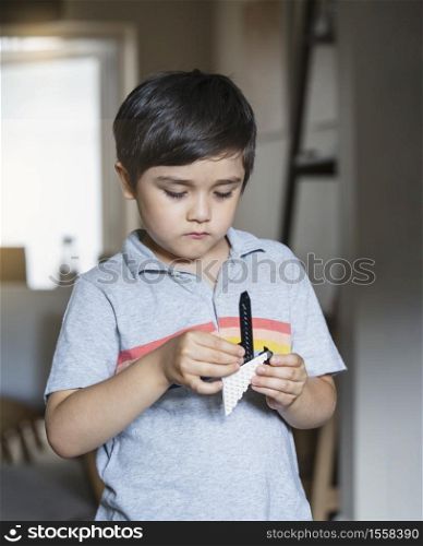Portrait kid playing plastic blocks, Child boy standing in living room concentrated bluiding his toys, Young boy relaxing at home on weekend in summer.