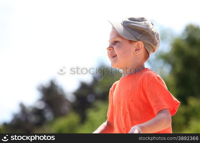 Portrait little boy kid in cap outdoor green background