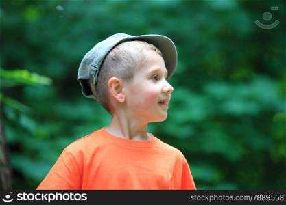 Portrait little boy kid in cap outdoor green bokeh background