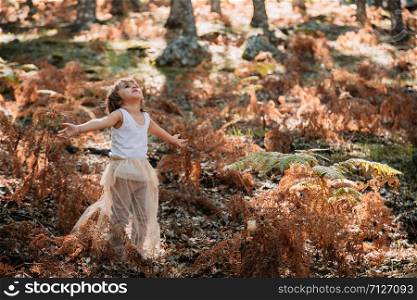 Portrait little caucasian baby girl in the forest among ferns watching away