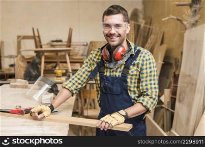 portrait male carpenter holding wooden plank workbench workshop