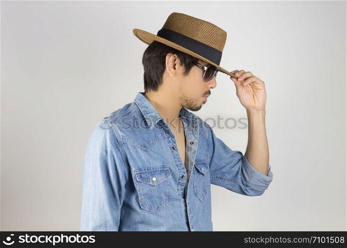 Portrait Man in Jeans Shirt or Denim Shirt and Glasses or Eyewear and Touch Hat. Man in Jeans Shirt or Denim Shirt with brown straw hat wear black glasses or eyewear on grey background in smart style