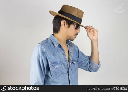 Portrait Man in Jeans Shirt or Denim Shirt and Glasses or Eyewear and Touch Hat. Man in Jeans Shirt or Denim Shirt with brown straw hat wear black glasses or eyewear on grey background in smart style