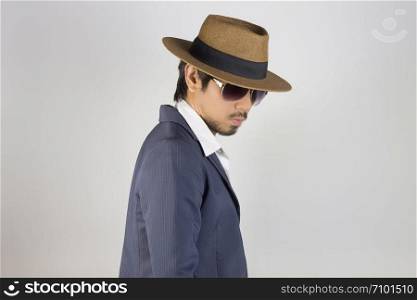 Portrait Man in Navy Blue Suit and White Shirt and Hat and Glasses on Right Pose. Man in Navy Blue suit with brown straw hat and black glasses or eyewear on grey background in smart style