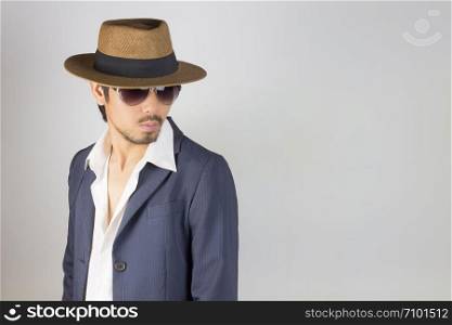 Portrait Man in Navy Blue Suit and White Shirt and Hat and Glasses Turn Back Pose. Man in Navy Blue suit with brown straw hat and black glasses or eyewear on grey background in smart style