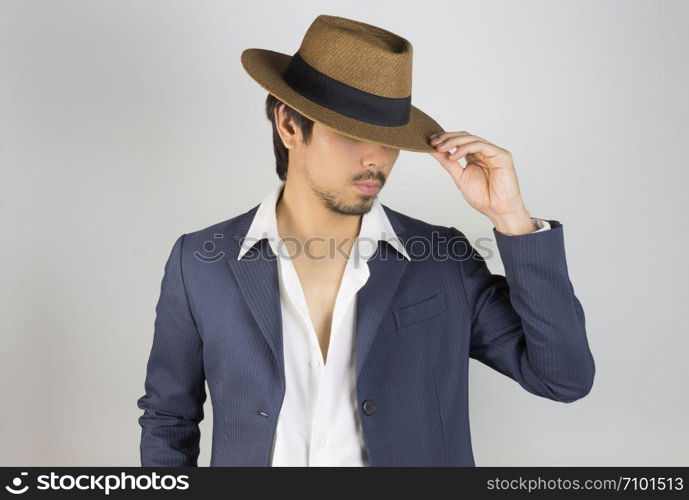 Portrait Man in Navy Blue Suit and White Shirt and Hat Fashion on Front Side View. Man in Navy Blue suit with brown straw hat on grey background in smart style
