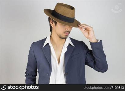 Portrait Man in Navy Blue Suit and White Shirt and Hat Fashion on Front Side View. Man in Navy Blue suit with brown straw hat on grey background in smart style