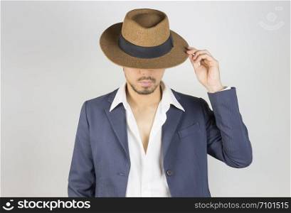 Portrait Man in Navy Blue Suit and White Shirt and Hat Fashion on Front View. Man in Navy Blue suit with brown straw hat on grey background in smart style