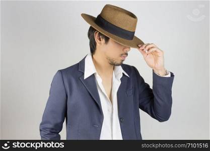 Portrait Man in Navy Blue Suit and White Shirt and Hat Fashion on Side View. Man in Navy Blue suit with brown straw hat on grey background in smart style