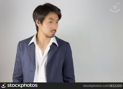 Portrait Man in Navy Blue Suit Looking Below. Portrait man in navy blue suit and white shirt on left frame of grey background in smart style