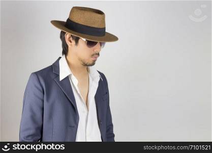 Portrait Man in Navy Blue Suit White Shirt and Hat and Glasses Fashion on Front Side View. Man in Navy Blue suit with brown straw hat and black glasses or eyewear on grey background in smart style