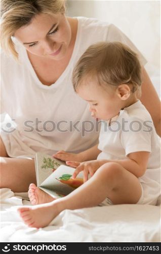 portrait mom reading baby bed