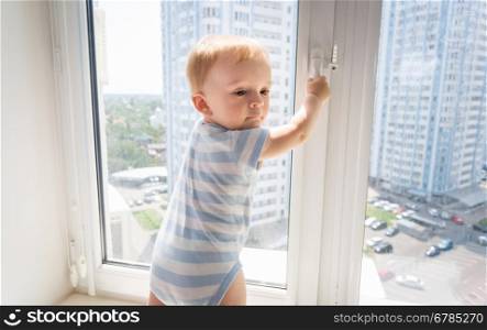 Portrait of 10 months old baby boy trying to open window