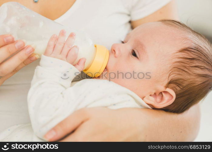 Portrait of 3 months old baby eating milk from bottle