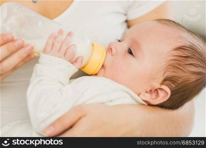 Portrait of 3 months old baby eating milk from bottle