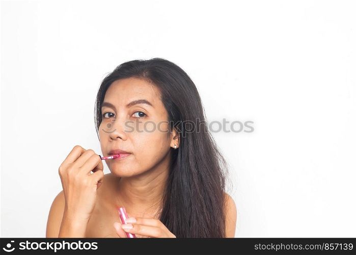 Portrait of 40s Asian woman applying lips gloss on her lips. Healthy and Beauty concept. Anti aging and surgery.