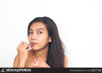 Portrait of 40s Asian woman applying lips gloss on her lips. Healthy and Beauty concept. Anti aging and surgery.