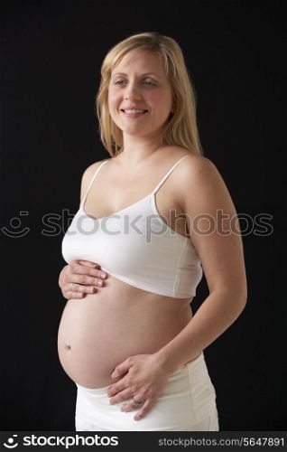 Portrait Of 5 months Pregnant Woman Wearing White On Black Background